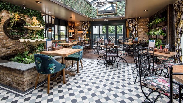 Un restaurant doté d’un sol à carreaux, de murs en briques et de différents types de sièges, notamment des tables et des chaises.