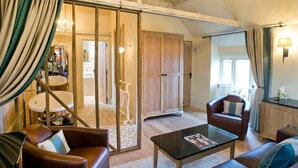 A cozy living room with leather sofas, a glass coffee table, and a sliding door leading to a kitchen. - The Fox Inn by Greene King Inns (Bury St Edmunds)