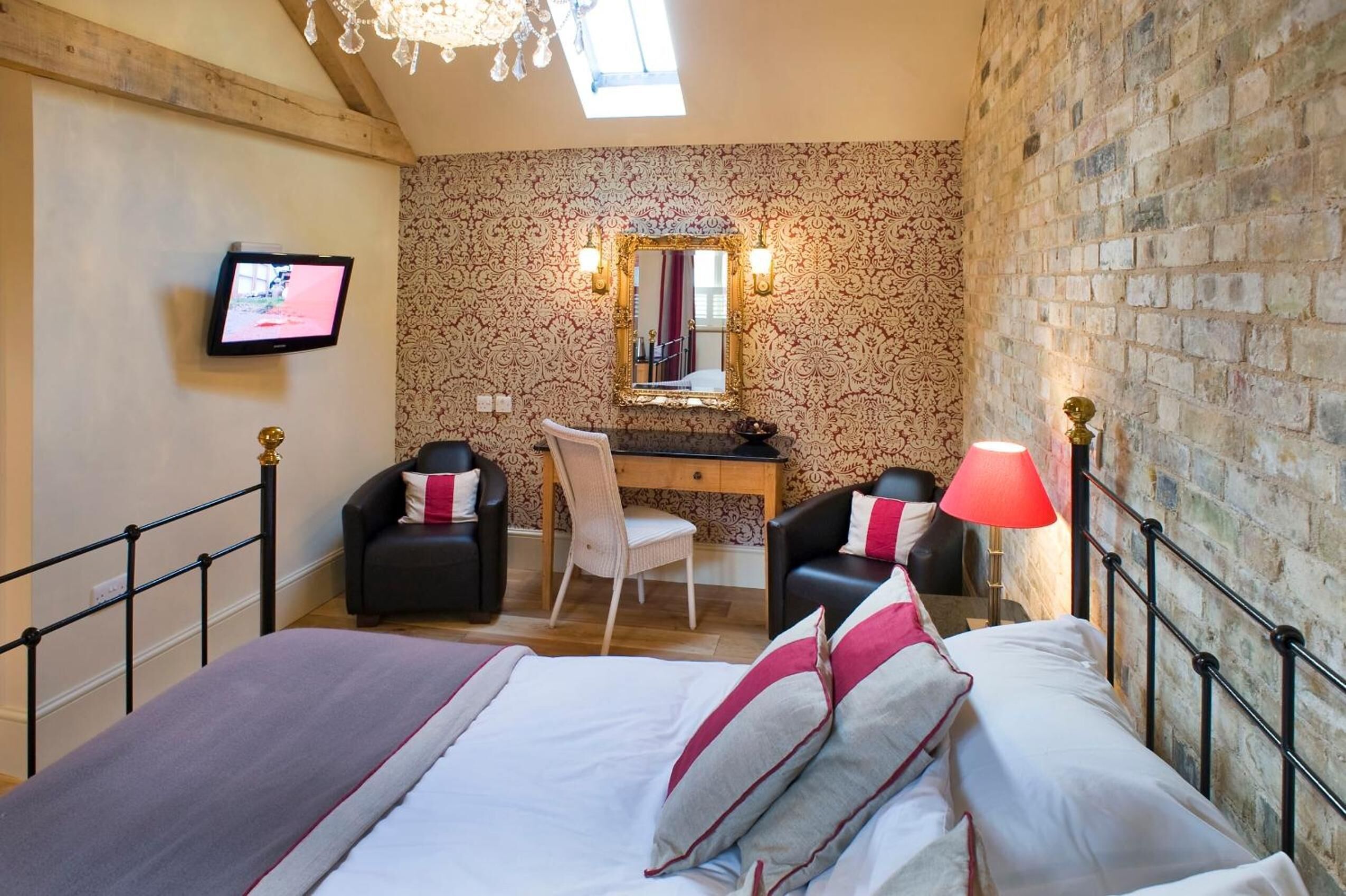Une chambre à coucher avec un lit, deux chaises, un bureau, un miroir et un téléviseur.