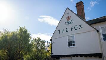 Een gebouw met een bord waarop 'GREENE KING 1799 THE FOX' staat, en een kroon erboven.