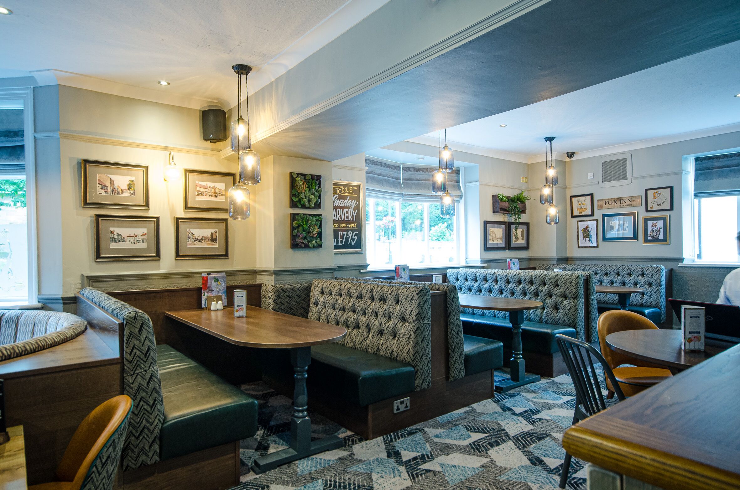 A restaurant interior with booths, tables, and hanging light fixtures.