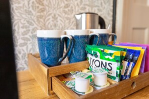 A wooden tray with blue ceramic mugs, a green and white bag labeled "YONONS," and some small white containers.