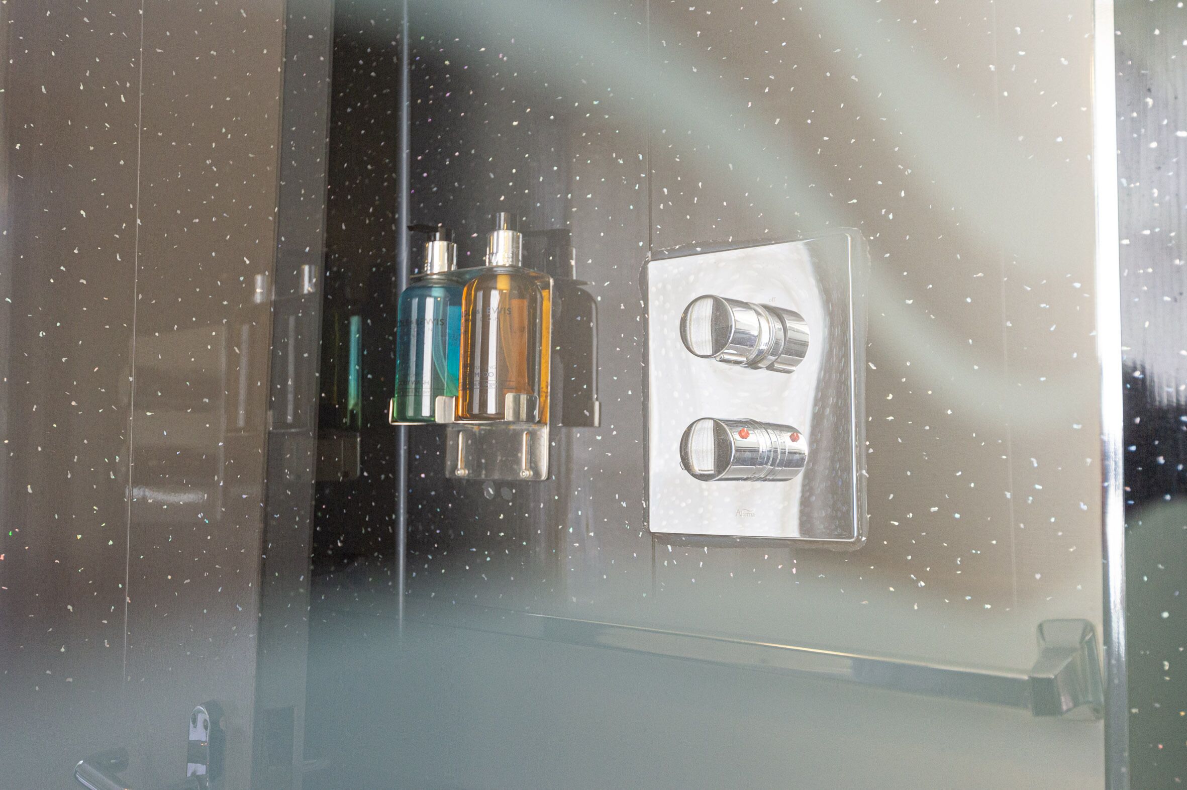 A bathroom with a glass shower enclosure, a towel rack, and a mirror.