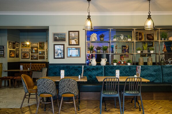 A restaurant with a bar area, seating, and a wall decorated with framed photos and plants. - The Fox Inn (Guisborough)