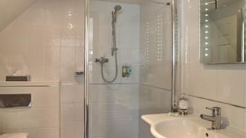 A modern bathroom with a glass-enclosed shower, a white sink, and a toilet.