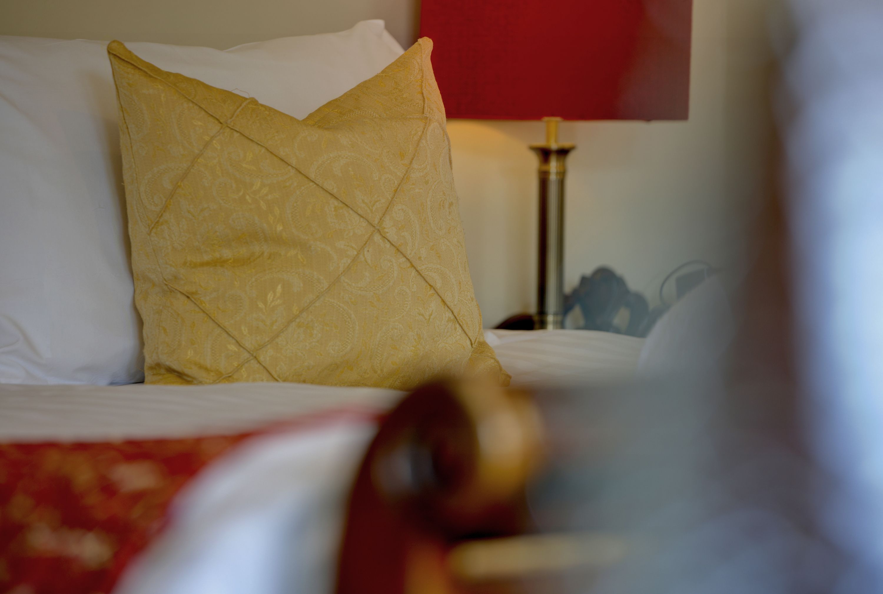 Una cama con un cojín estampado y una colcha roja.