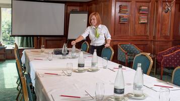 A conference room with a long table set for a meeting, a projector screen, and wooden paneling on the walls.