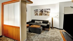 A modern living room with a sofa, ottoman, and a flat-screen TV. - SpringHill Suites By Marriott Columbia Fort Meade Area (Columbia)