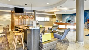 A modern hotel lobby with a reception desk, seating area, and a large pillar. - SpringHill Suites By Marriott Columbia Fort Meade Area (Columbia)