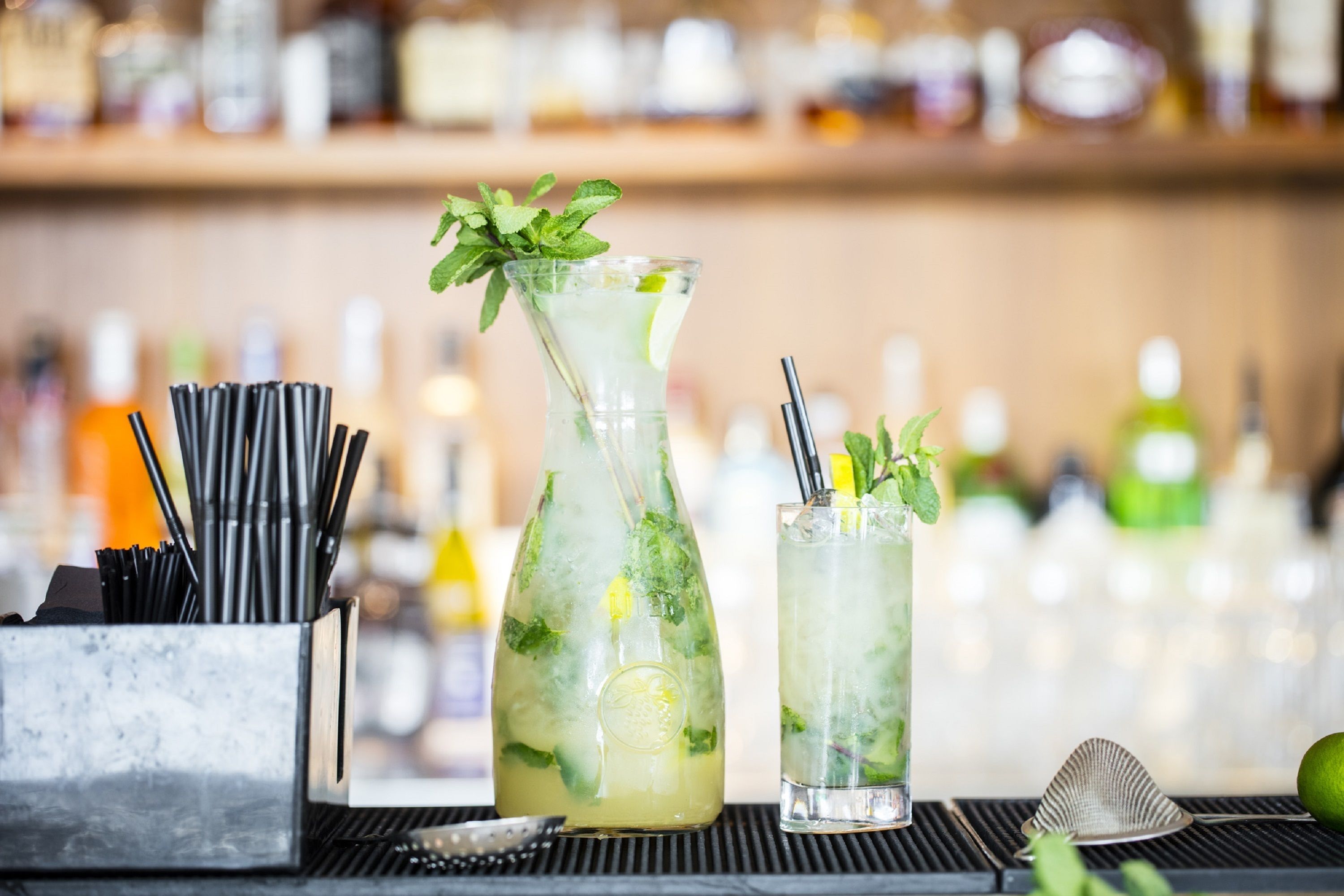 Um bar com duas bebidas, um coqueteleira e uma garrafa de licor.