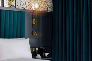 A hotel room with teal curtains, a white bed, a wall-mounted lamp, a coffee machine, and a cup on a small table. - DoubleTree by Hilton Hotel Leeds City Centre (Leeds)