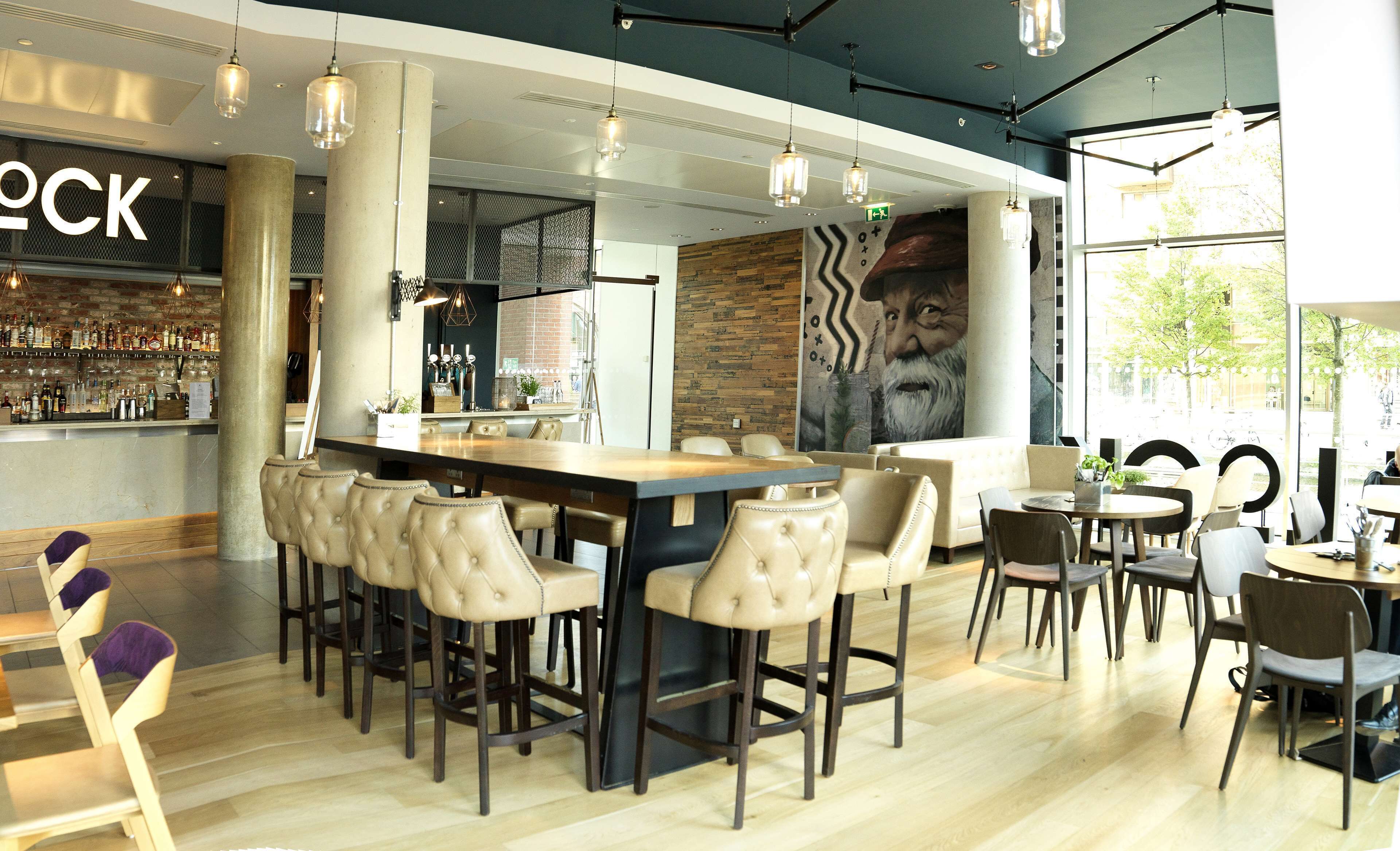 A modern bar area with leather barstools, a wooden bar counter, and pendant lighting.