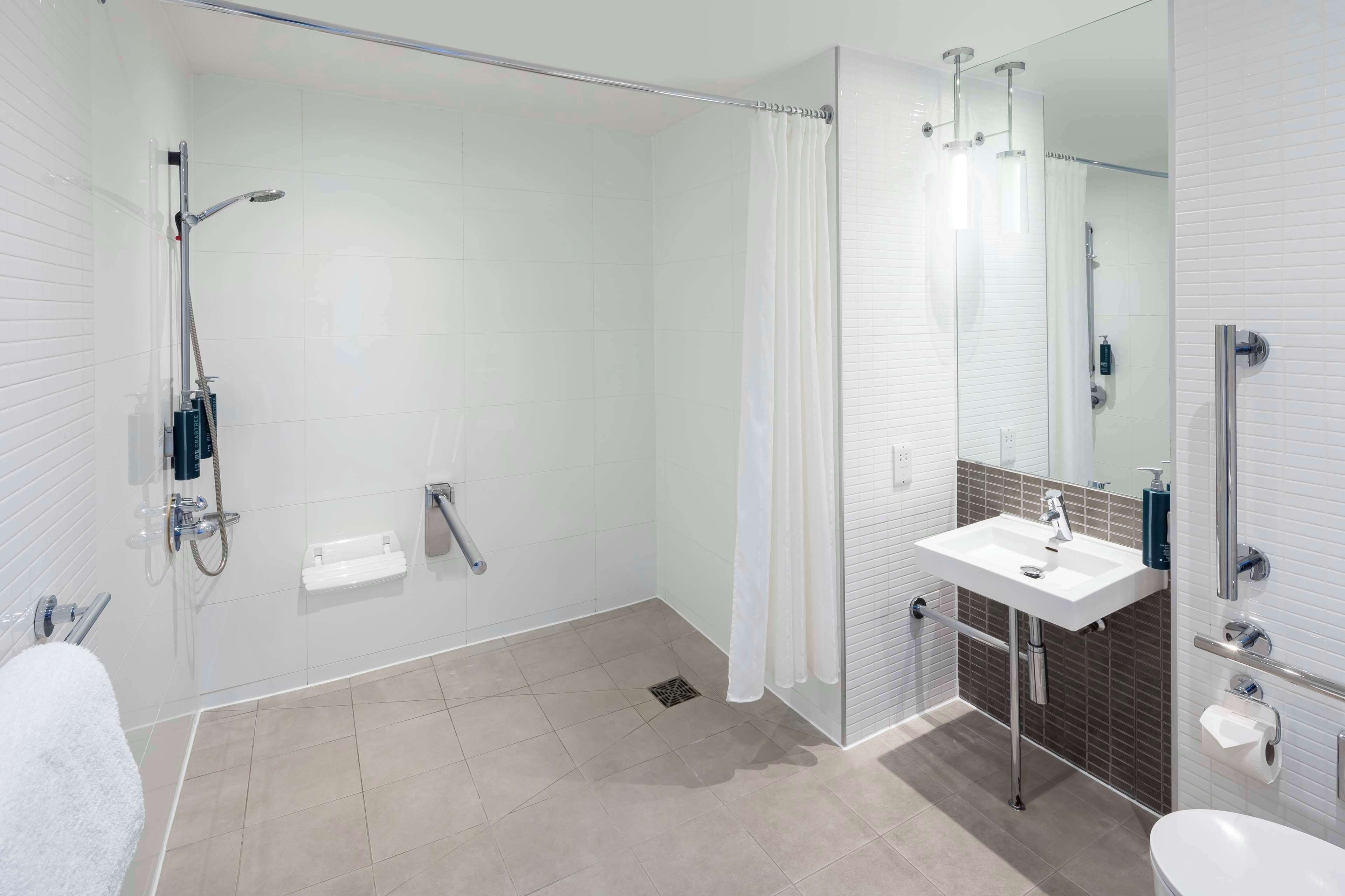 A modern bathroom with a glass-enclosed shower, a white sink, and a mirror.