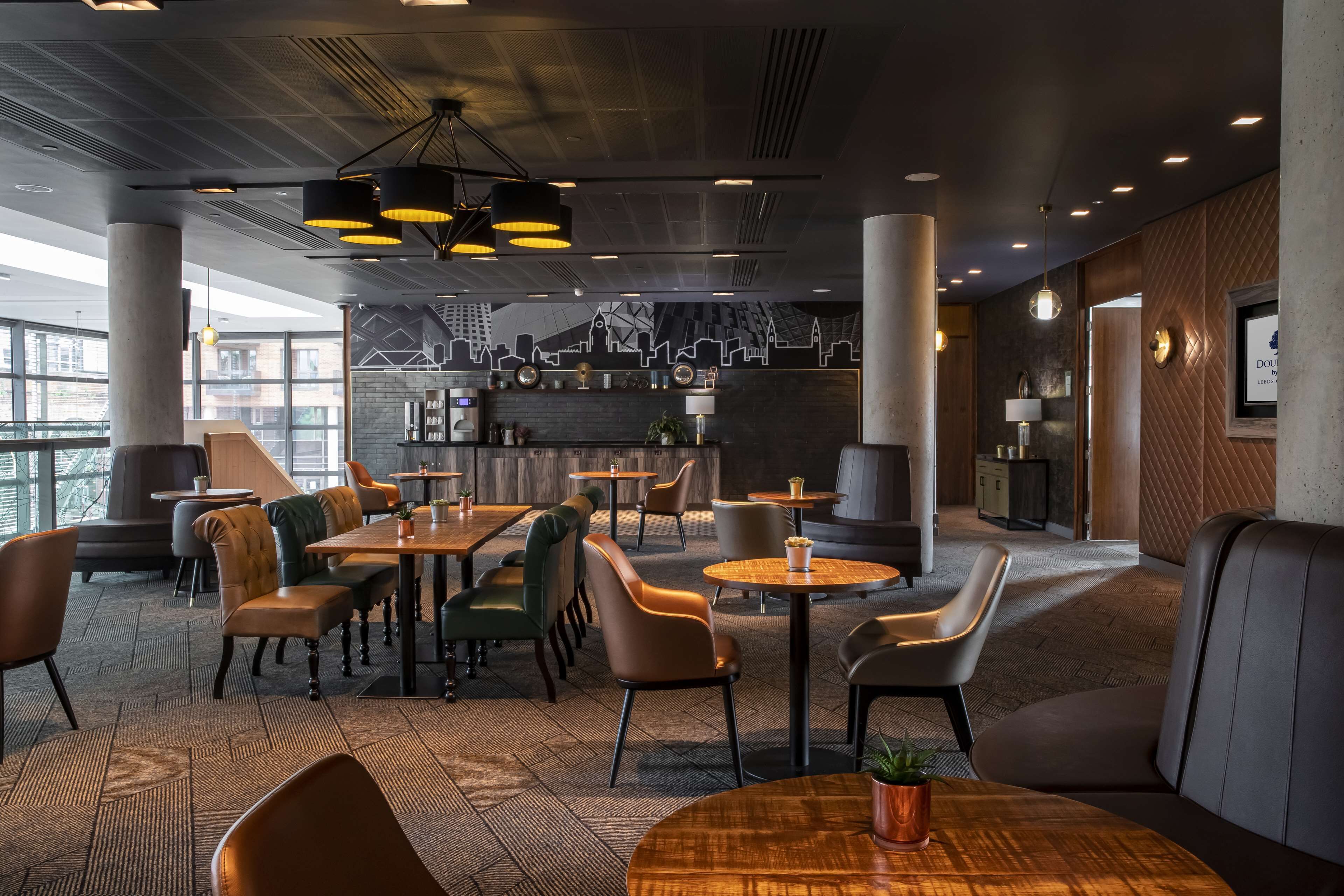 A modern restaurant with round tables, cushioned seating, and pendant lighting.
