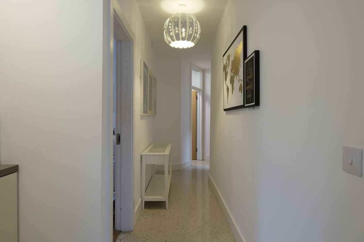 A hallway with a white door, a small white table, and a globe artwork on the wall.