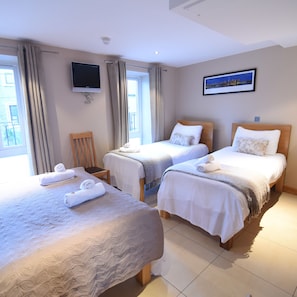 A hotel room with two beds, a TV, and a window with curtains. - Eyre Square Townhouse (Galway)