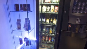 A vending machine with a variety of snacks and drinks, next to a glass display case with items. - Hostal Santo Domingo (Madrid)