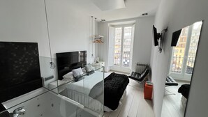 A modern bedroom with a large bed, a glass-enclosed bathtub, and a balcony with a view of the city. - Hostal Santo Domingo (Madrid)