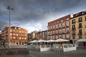 A street with buildings, a kiosk, and a lamppost. - Hostal Santo Domingo (Madrid)