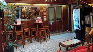 Un rincón de bar con taburetes de madera, una araña y un refrigerador con dispensador de agua.