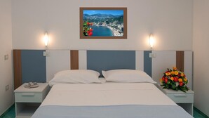 A hotel room with a bed, two bedside tables, a nightstand, a wall-mounted picture, and a flower arrangement. - Hotel De Rosa (Maiori)