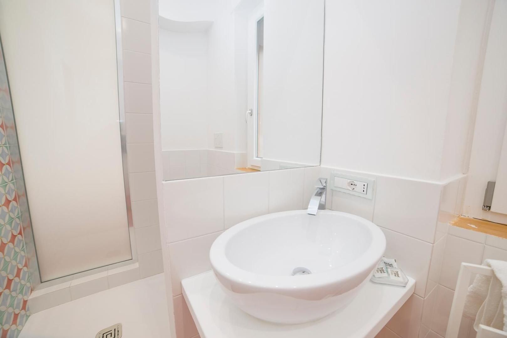 Ein Badezimmer mit einem weißen Waschbecken, Spiegel und Fliesenwänden.