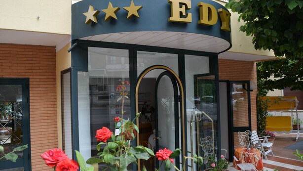 L’entrée d’un hôtel, avec une façade incurvée, un logo en forme d’étoile et une porte en verre.