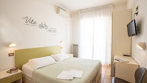 Une chambre d’hôtel bien aménagée, avec un lit, un bureau, une chaise, une télévision et un mur orné d’une citation inspirante.