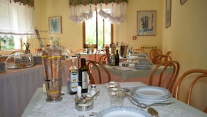 Un espace repas avec des tables dressées pour le service, comprenant de la vaisselle en verre, des assiettes et des couverts.