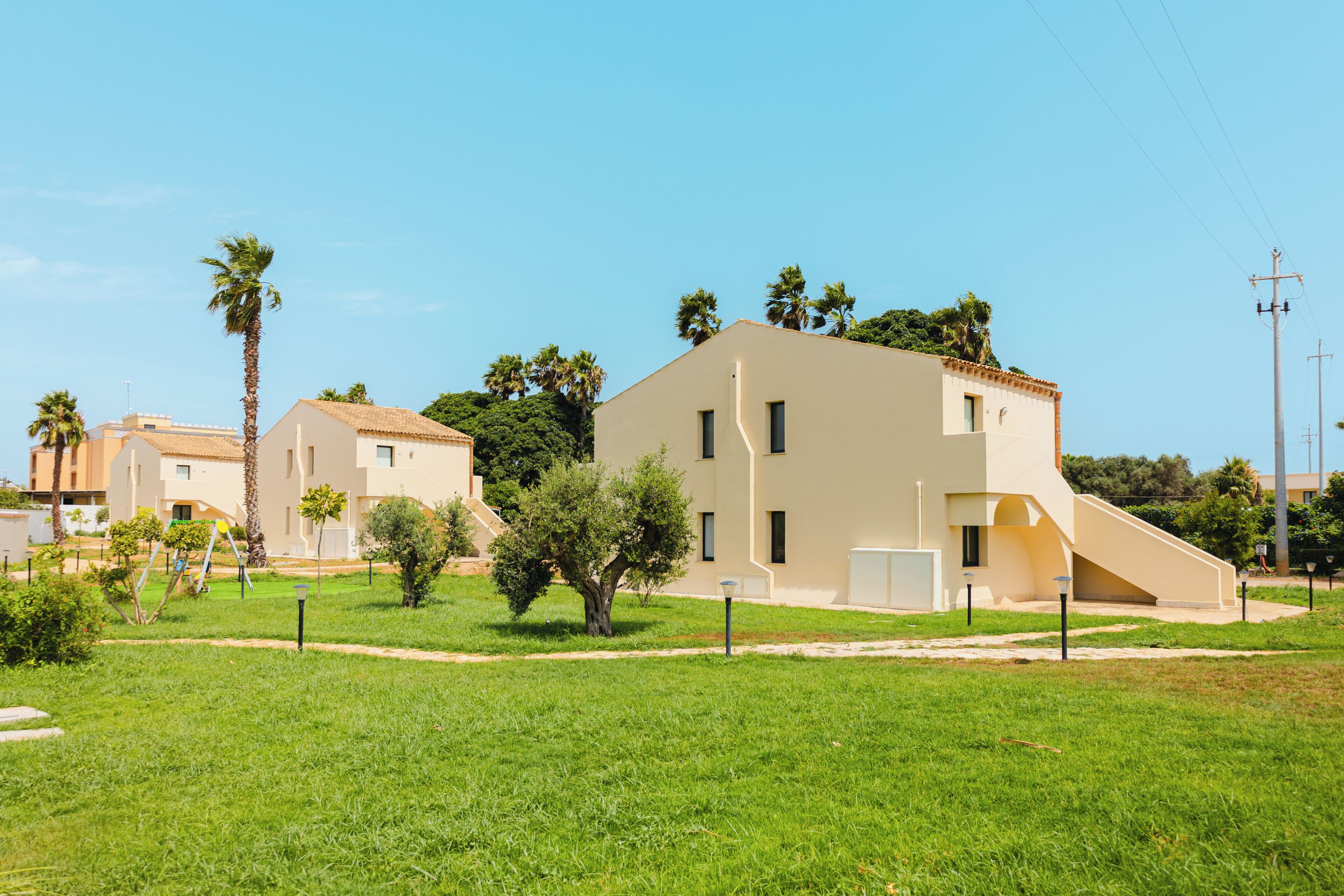 Un quartiere residenziale con edifici moderni, un prato verde e cielo sereno.