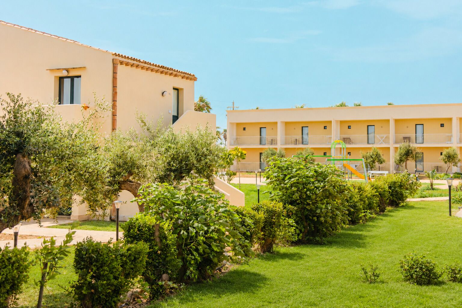 A hotel with a courtyard, including a playground and lush greenery.