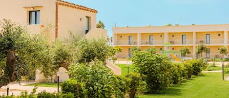 A hotel with a courtyard, including a playground and lush greenery.