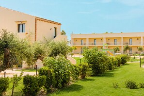 Un hotel con un patio que incluye un parque infantil y abundante vegetación.