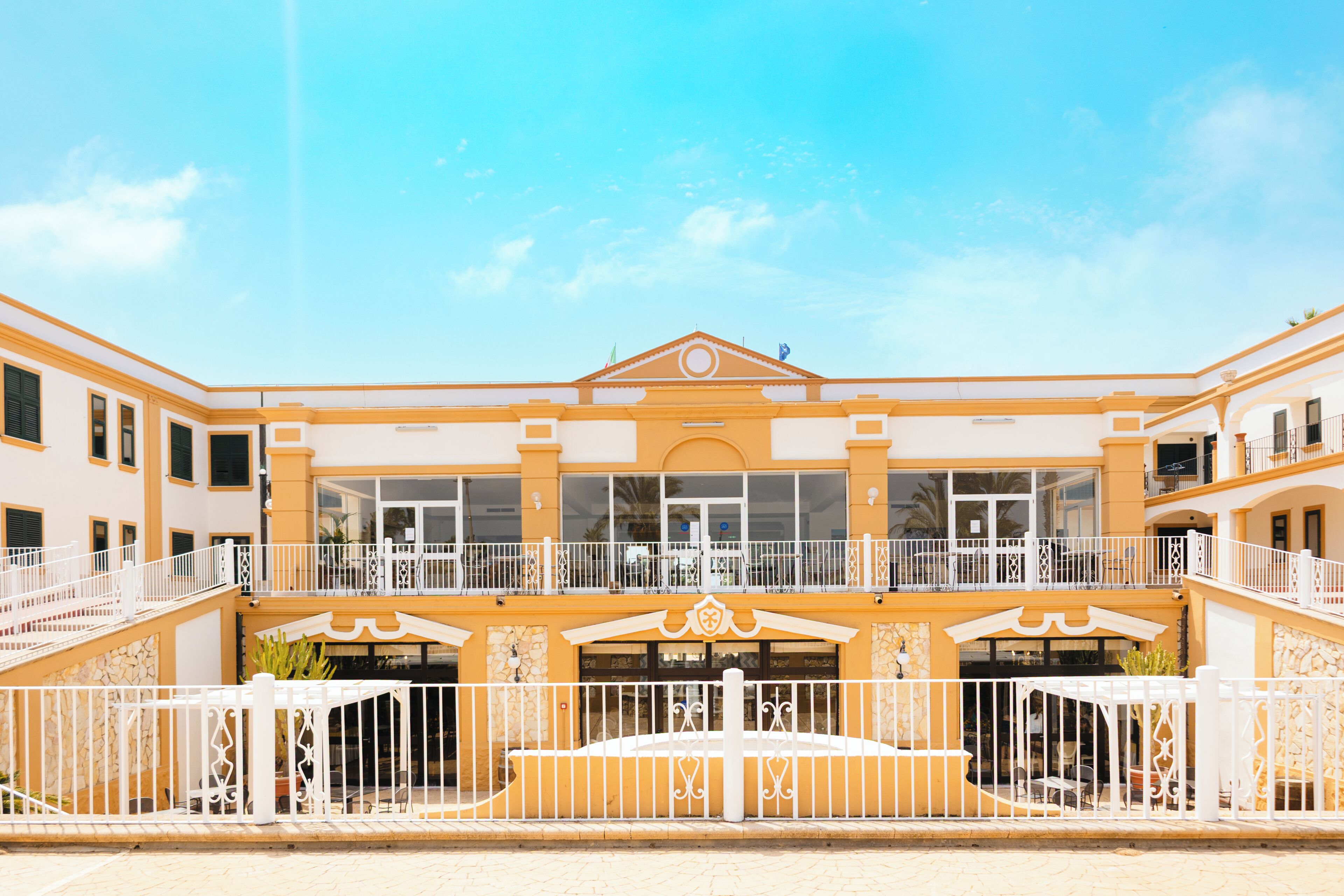 A hotel with a central courtyard, multiple balconies, and a symmetrical facade.