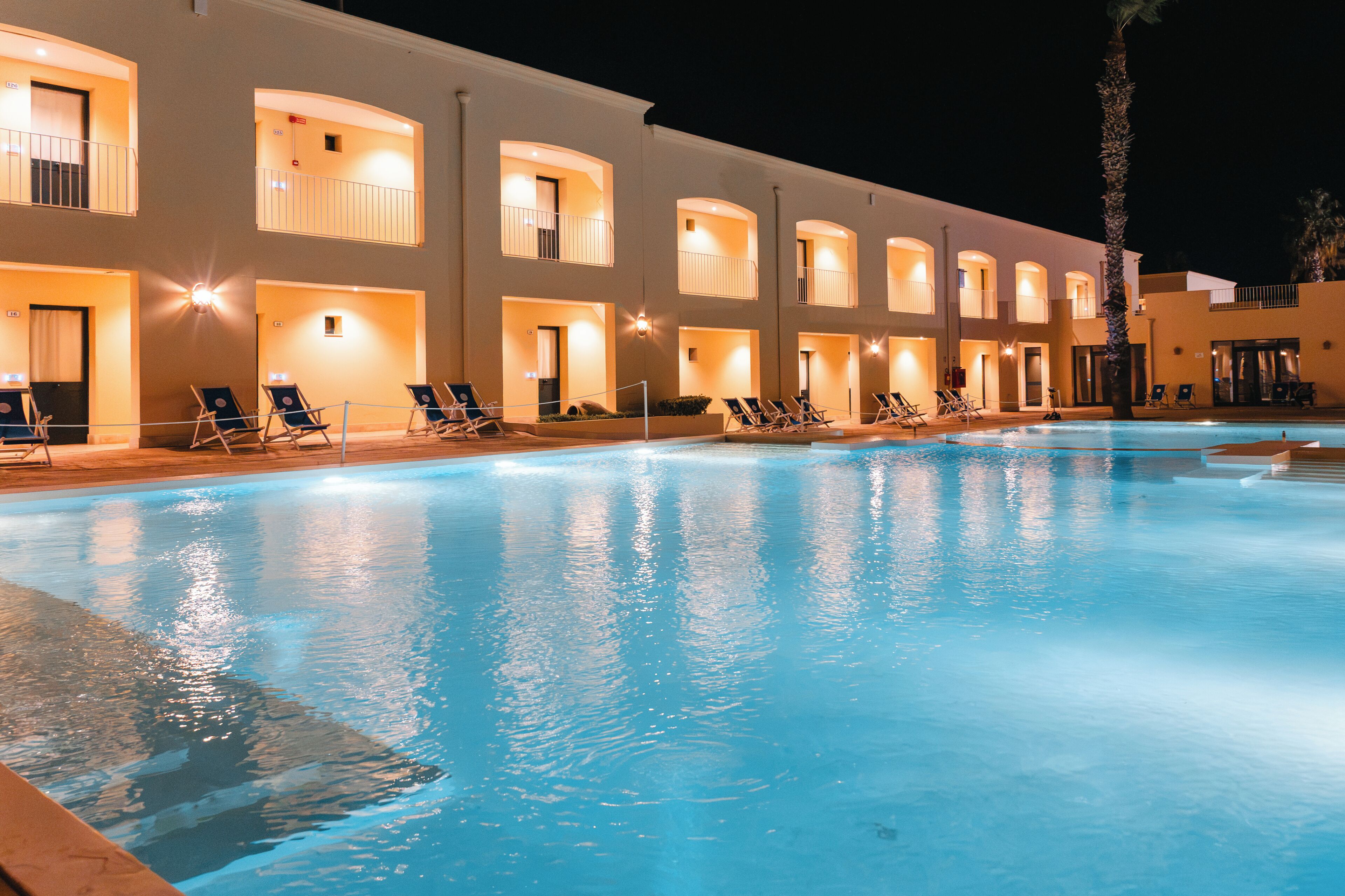 Un hotel con piscina, diversi balconi e sedie a sdraio.