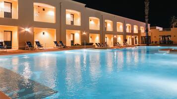 Un hotel con piscina, diversi balconi e sedie a sdraio.