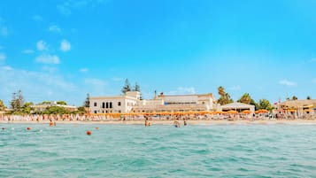 Ein Strand mit einem Gebäude im Hintergrund.