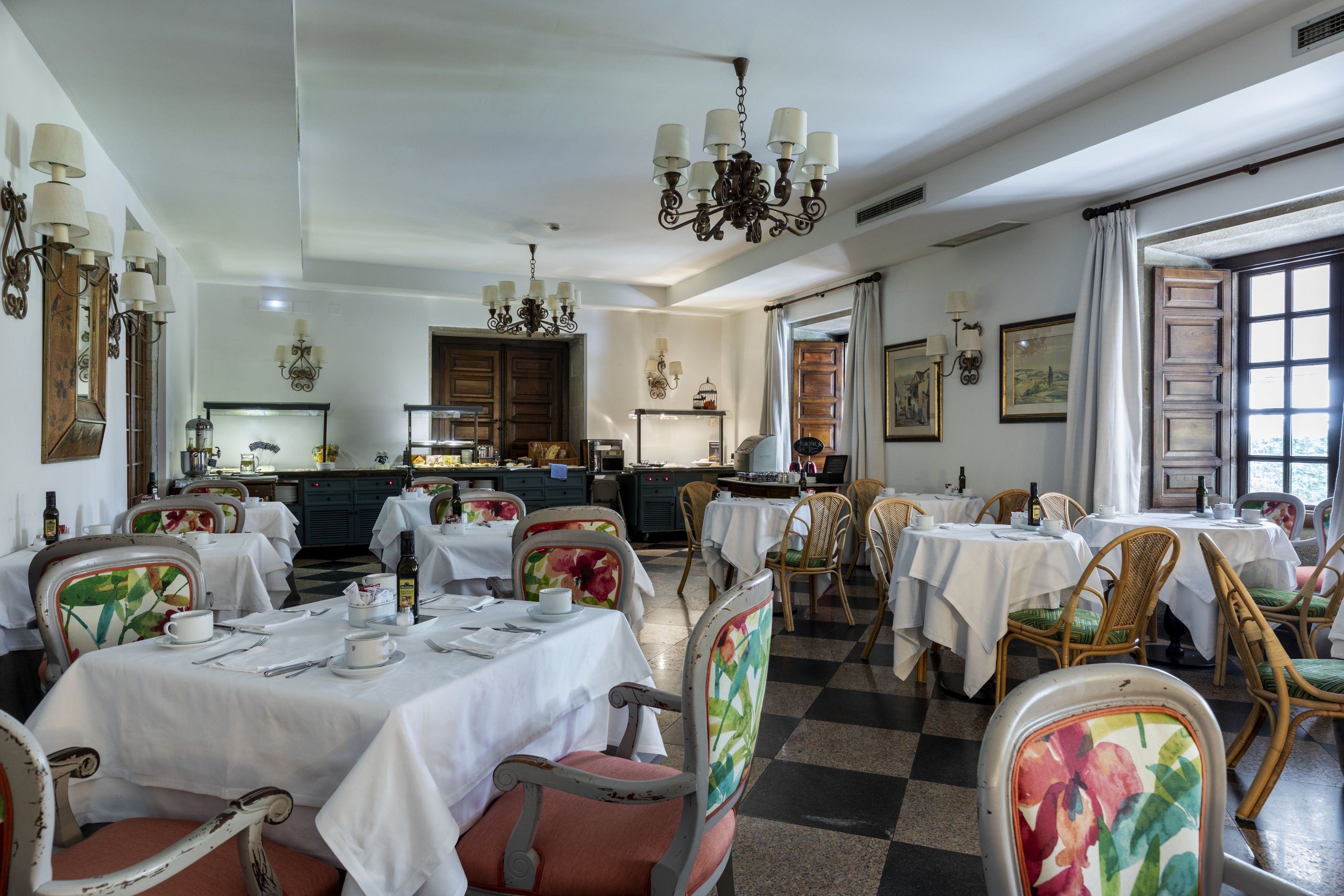 Ein Essbereich mit gedeckten Tischen, Stühlen mit floralem Bezug und einer Chandelier.