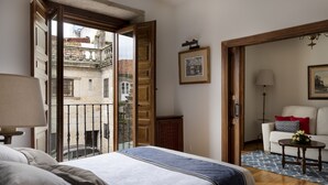 A bedroom with a bed, a balcony, a sofa, and a small table with flowers.