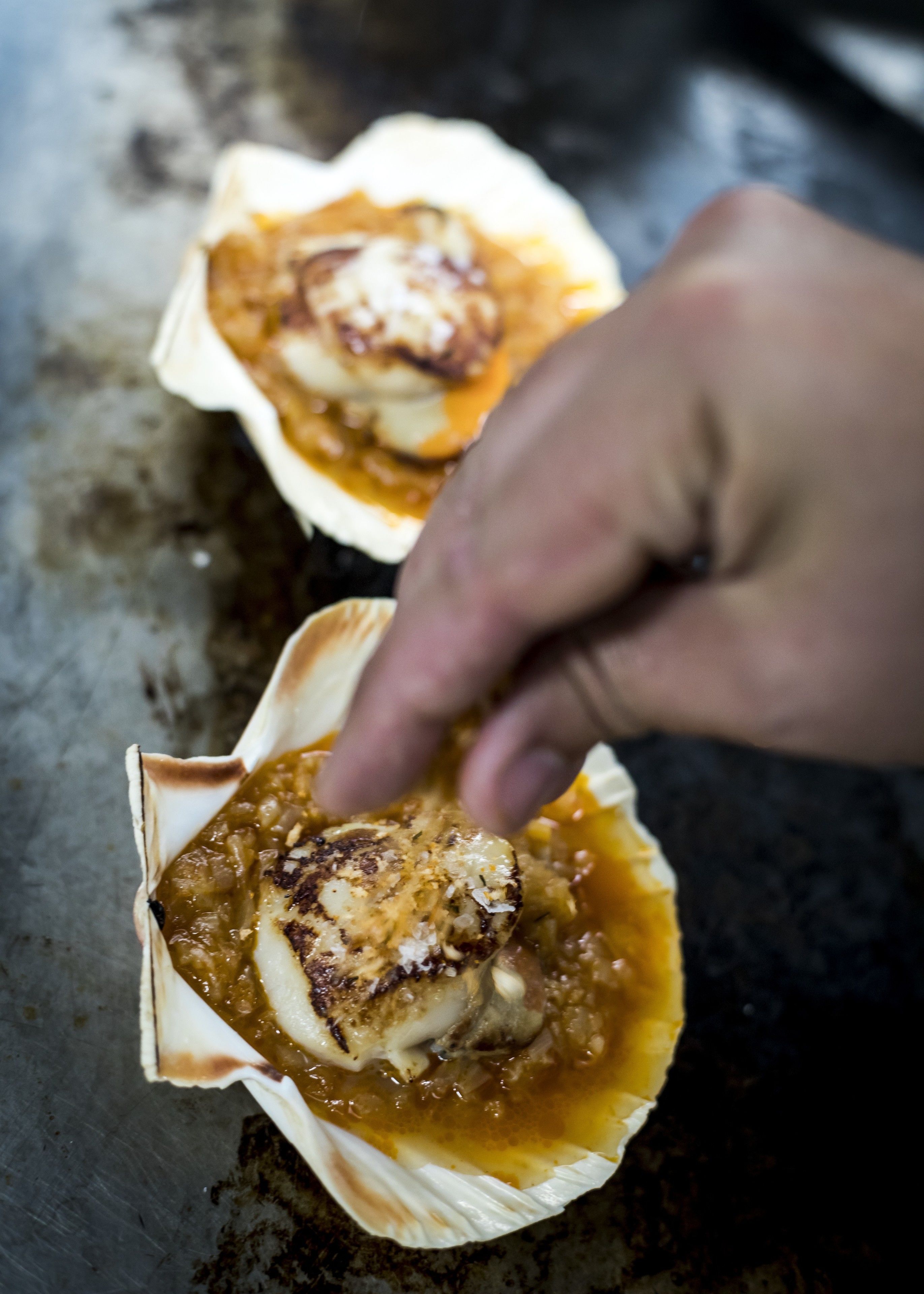 A hand placing a food item into a shell-like container.