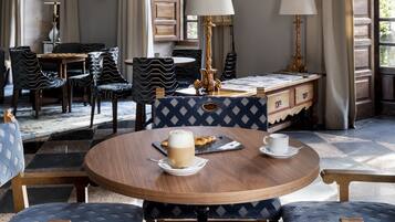 A room with a chandelier, round wooden table, patterned chairs, and a view of the outdoors.