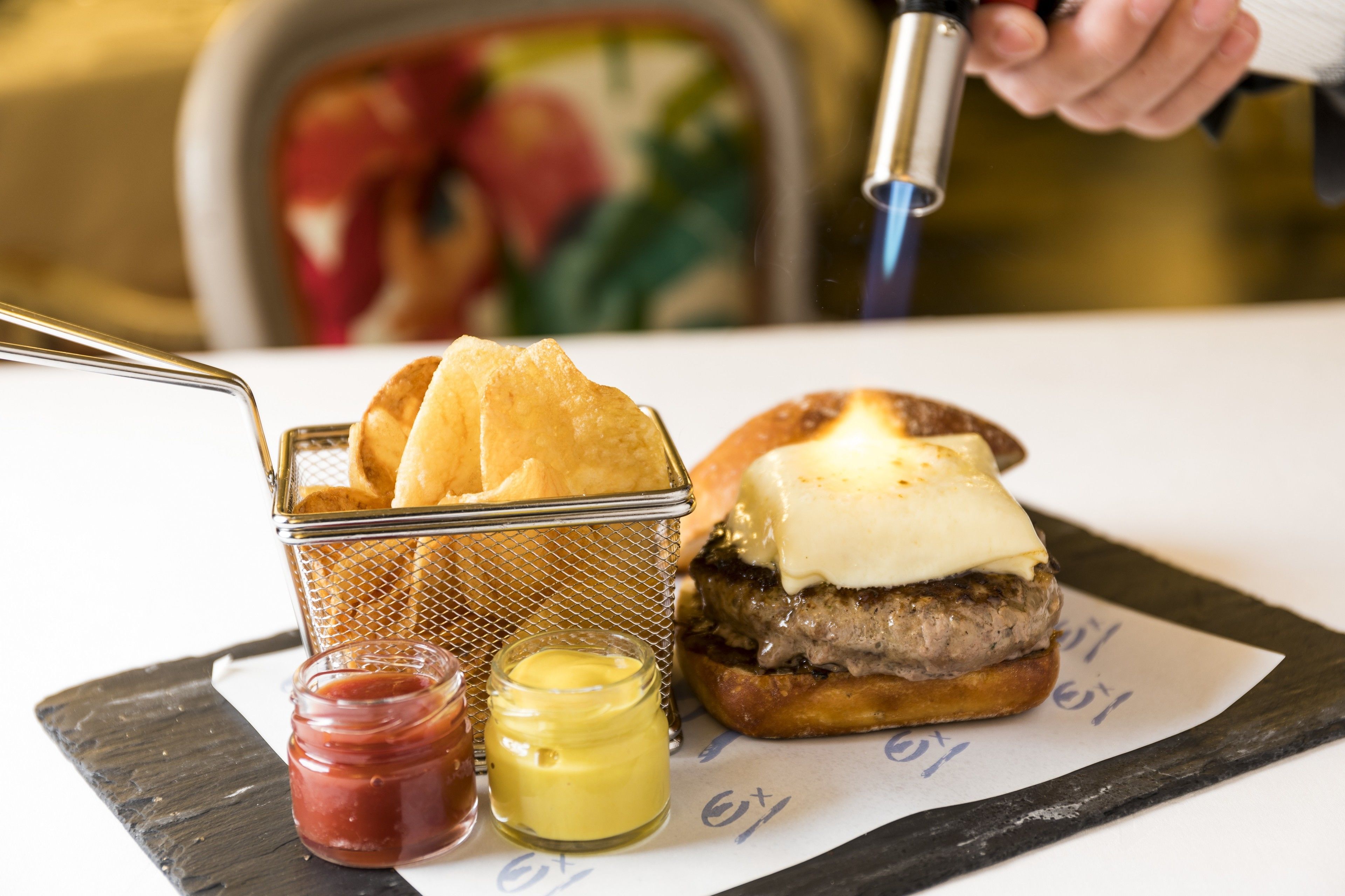 A sandwich with cheese and a side of chips, accompanied by ketchup and mustard.