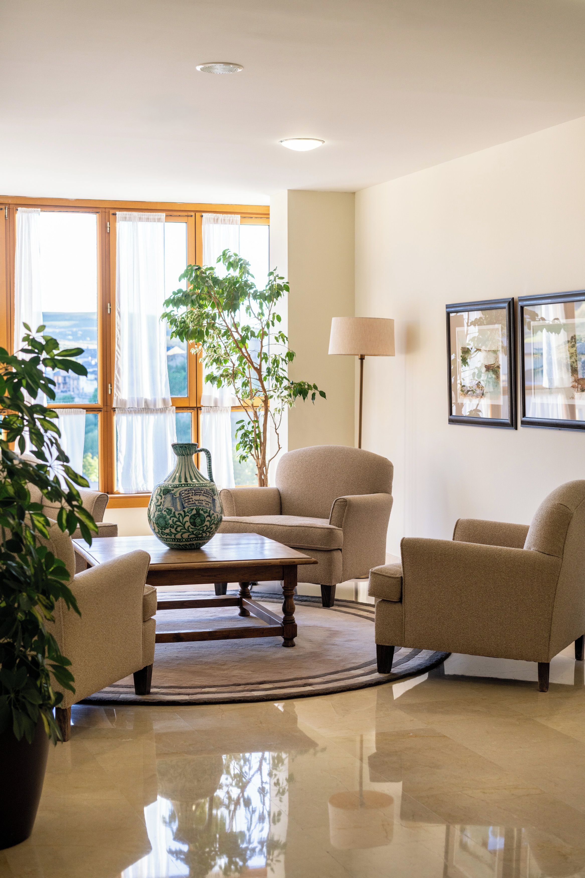 Un salón luminoso con un amplio ventanal, una mesa de centro y dos sillones.