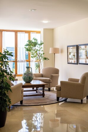 A well-lit living room with a large window, a coffee table, and two armchairs. - Parador de Puebla de Sanabria (Puebla de Sanabria)