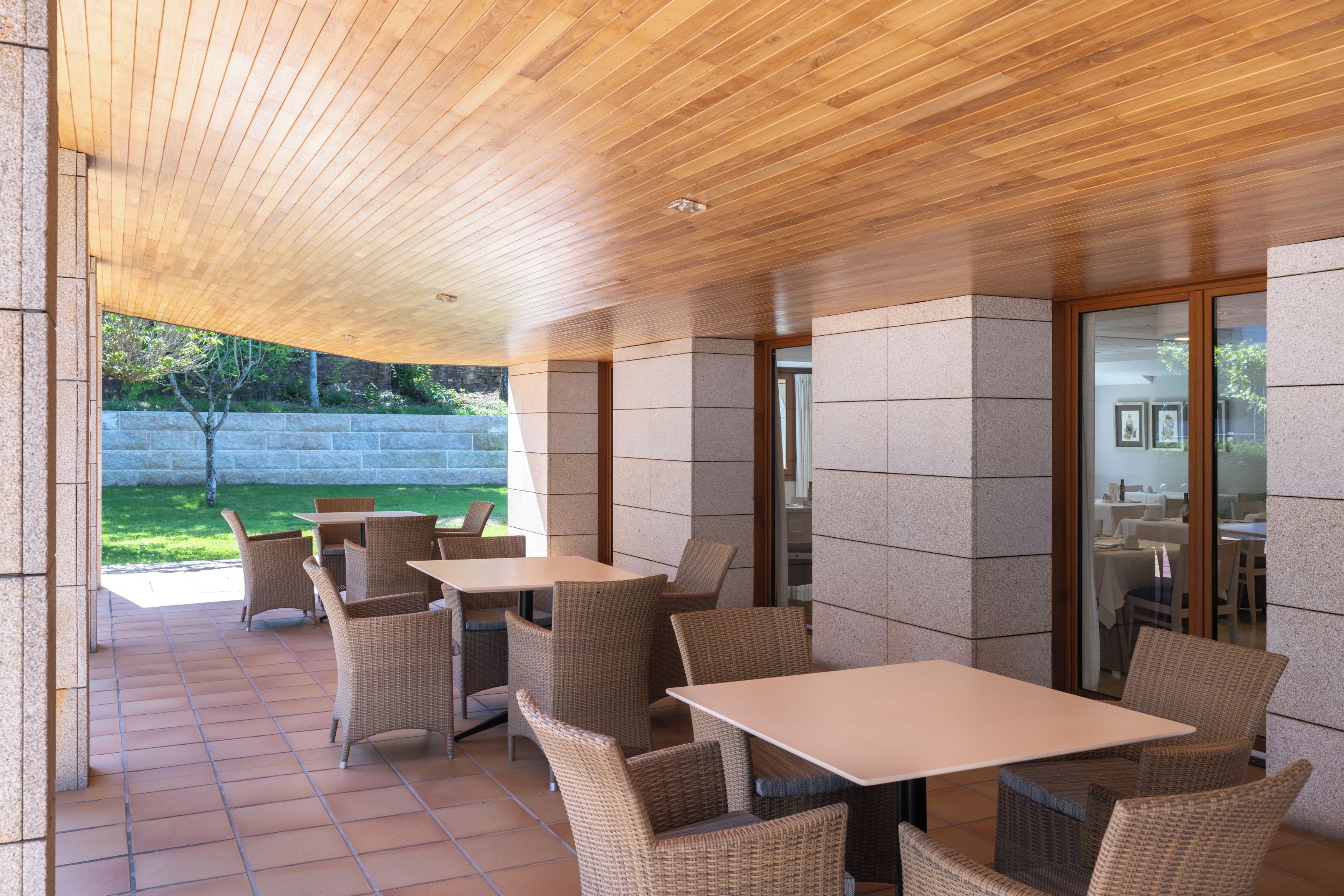 Un patio al aire libre con mobiliario de mimbre y techo de madera.