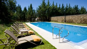 A swimming pool with lounge chairs and a stone wall. - Parador de Puebla de Sanabria (Puebla de Sanabria)