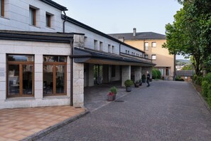 A building with a stone facade, a covered walkway, and potted plants. - Parador de Puebla de Sanabria (Puebla de Sanabria)