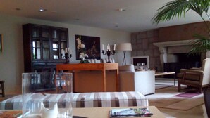 A modern living room with a wooden coffee table, a glass vase with a white object, and two magazines on the table. - Parador de Puebla de Sanabria (Puebla de Sanabria)