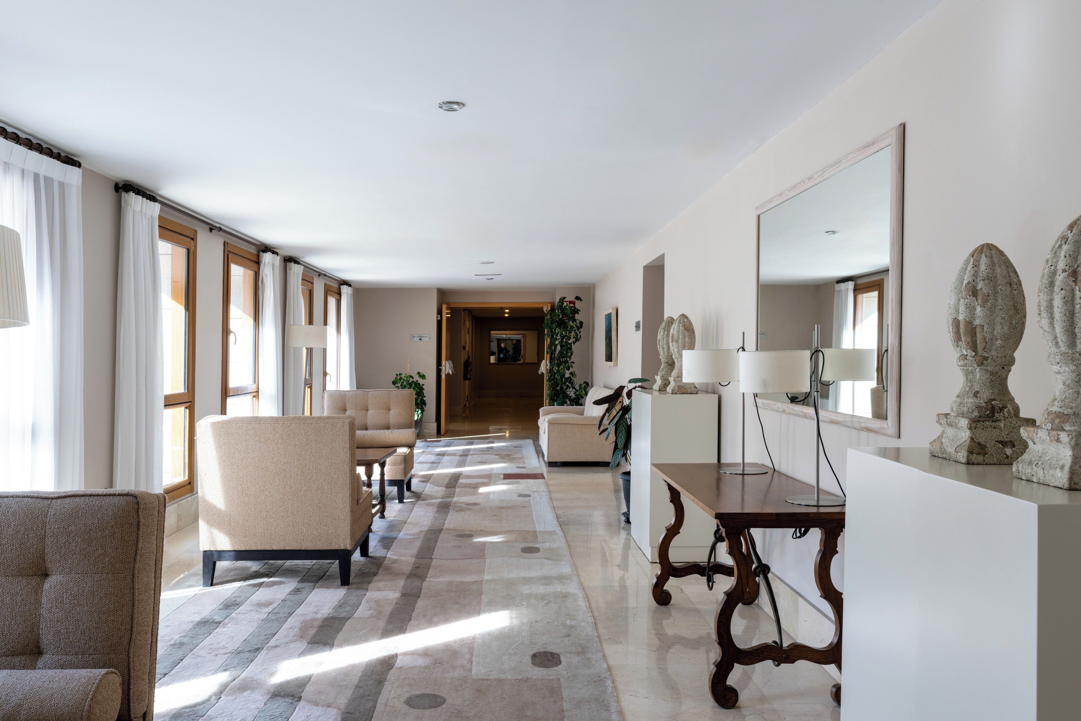 A hotel lobby with a long corridor, seating area, and a reception desk.