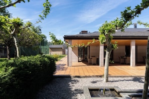 A modern outdoor patio area with a pergola, seating, and a water feature.